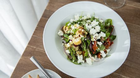 A large dish with salad topped with crumbled feta cheese.