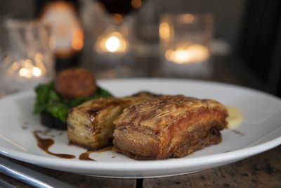 A candlelit Sunday lunch of roast pork with crackling served with a drizzle of gravy and greens.