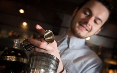 Mixologist wearing a white shirt and making a cocktail