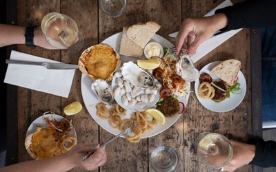 people eating plate with 3 Irish rock oysters on, two glasses of white wine served on the side