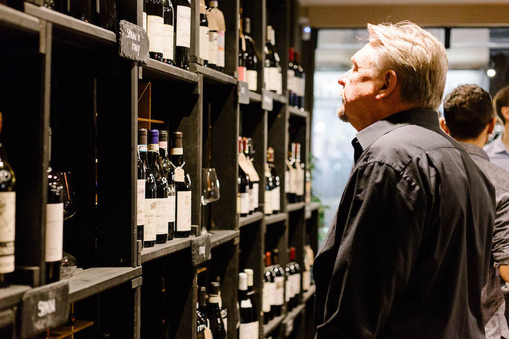 A man looking at shelf with wine as Cases Hove