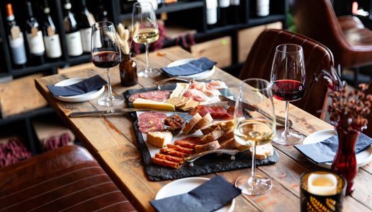table laid out with charcuterie and cheese board, and glasses of red and white wine at Cases Hove