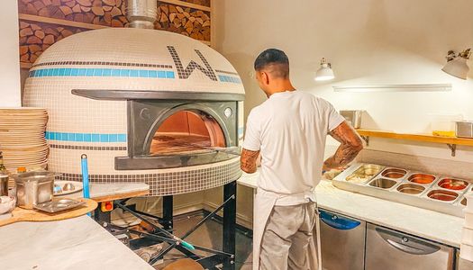 Chef cooking pizza at Woodbox Pizzeria in a pizza oven.
