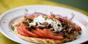 A plate of flatbread, slice tomatoes and meat at Adelfia Greek Restaurant Brighton