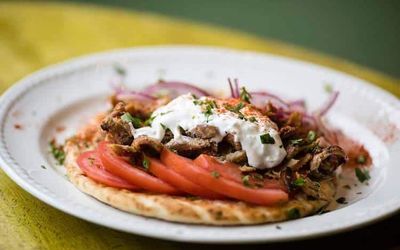 A plate of flatbread, slice tomatoes and meat at Adelfia Greek Restaurant Brighton. Located on Preston Street Brighton