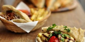 A basket of bread and fries alongside a side plate of artichokes and houmous