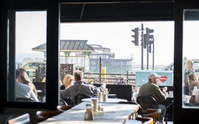 A view of the West pier taken from inside The New Club, looking through the open glass doors at alfresco diners