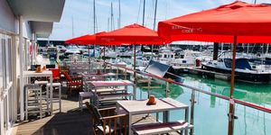 A row of tables with red parasols facing out on the Brighton marina front