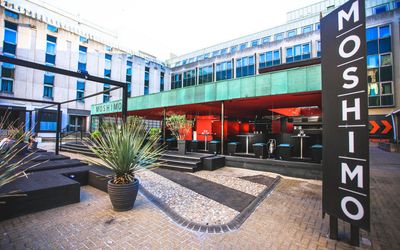 Alfresco seating at Moshimo on a sunny day. Pictured the Moshimo signage with offices in the background. Moshimo is one of the original Japanese or sushi restaurants in Brighton