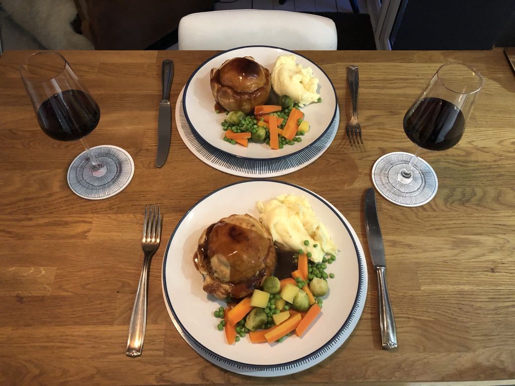overhead shot of two plates of homemade pies with mash, mixed veg and onion gravy