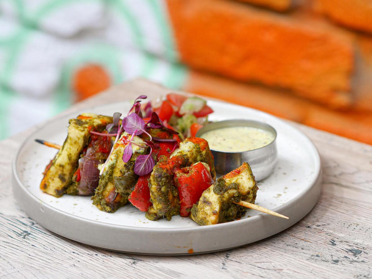 Paneer tikka skewers with a small metal pot of dipping sauce. Leisurely lunch ideas in Brighton. Curry Leaf Cafe
