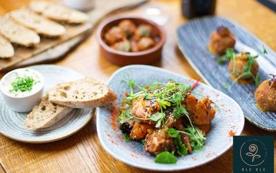 A selection of small plates of food with arancini balls, slices of fresh bread and bowls of dip.