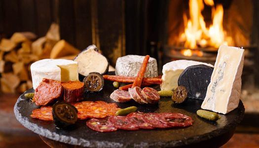 A Christmas gift idea. a Great British Charcuterie platter. Pictured salamis, cured meats and cheeses in front of a roaring fire.