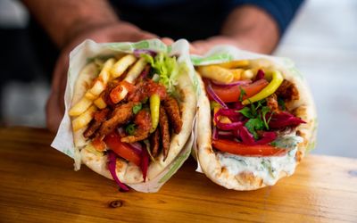 Two vegan flatbread kebabs with vegan donna meat, chips and salad.