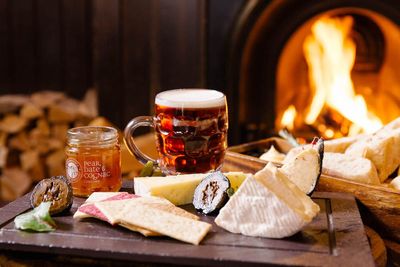 charcuteire board with glass full of beer with fire place in background