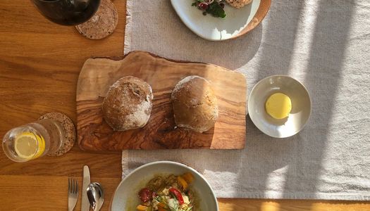 Rustic bowls of starters with Smoked Trout Rillette and Tomatoes with Baba Ghanoush, served alongside sourdough rolls.