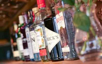 Spirits of alcohol on a wooden shelf with a vase of flowers