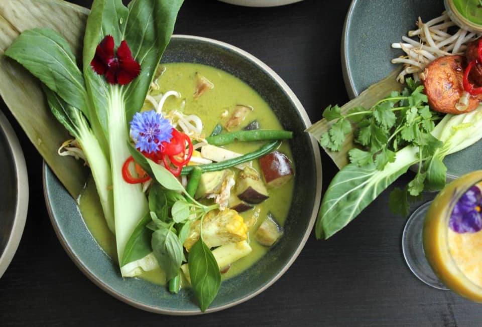 Green curry decorated with pak choi and edible flowers. 
