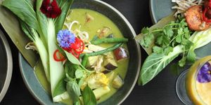 Green curry decorated with pak choi and edible flowers.