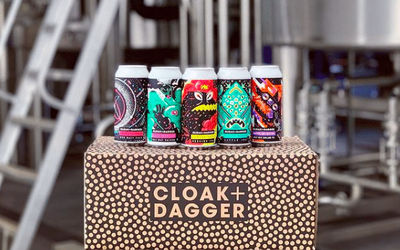 Craft beer cans on a box Colourful Cloak and Dagger Beer sat on their branded box