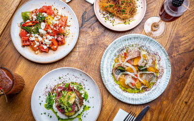 four plates of brunch shot from above with cocktails on a wooden table, romantic restaurants Brighton