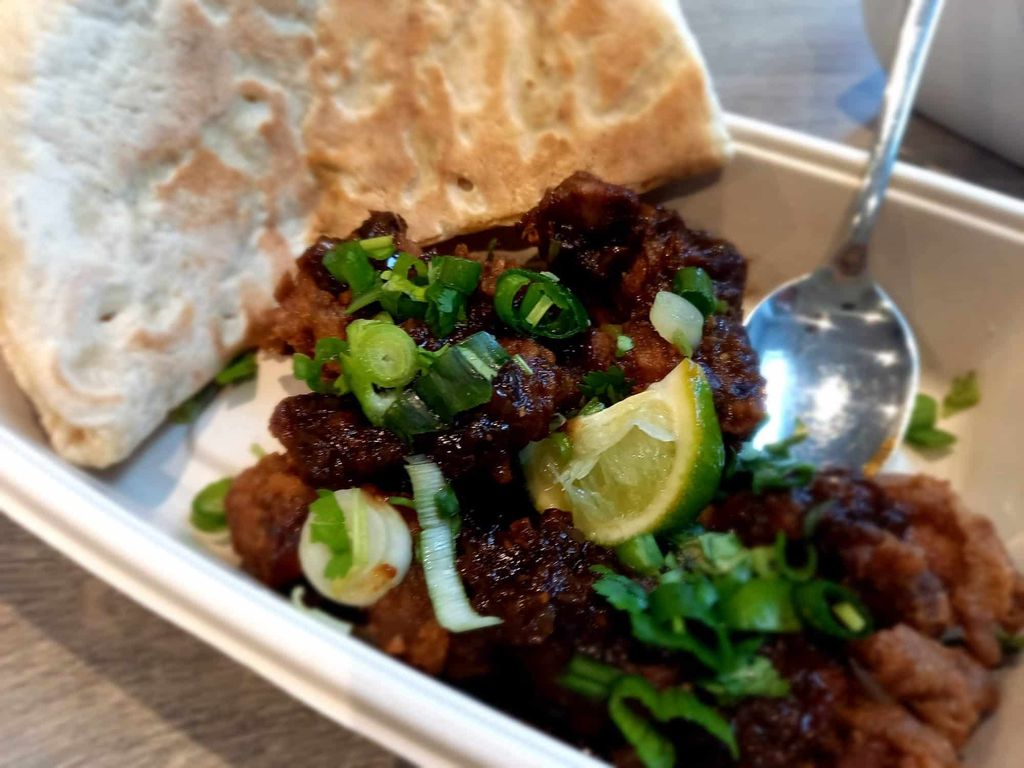 A close up of curry and naan in a takeaway container