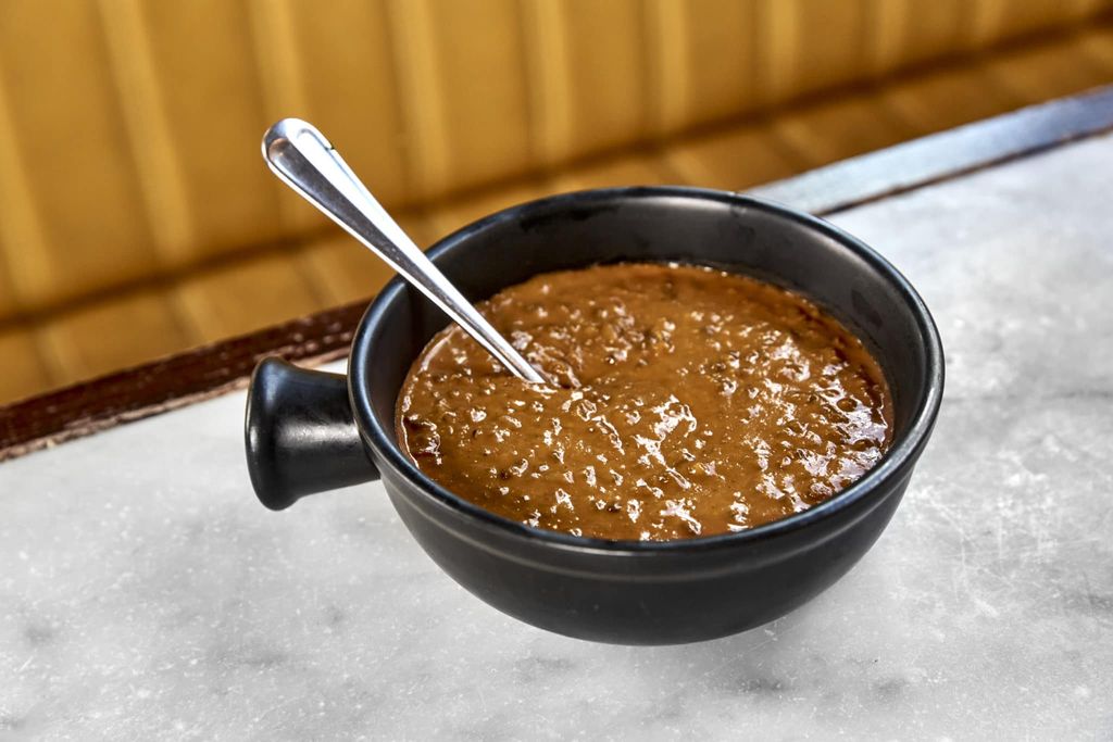 A bowl of daal with a spoon in it