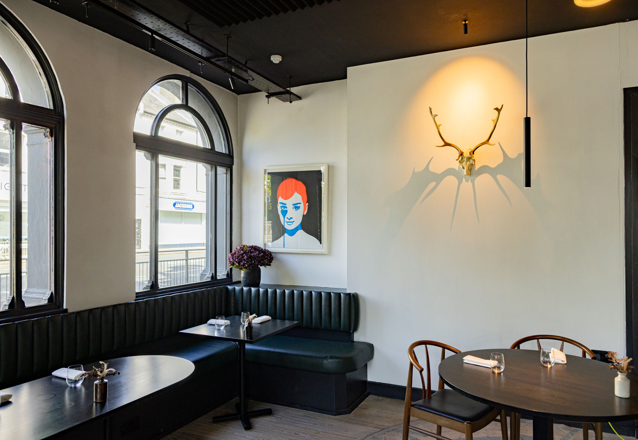 the elegant interior of etch . dark banquet seating. artwork and antlers on the wall. 
