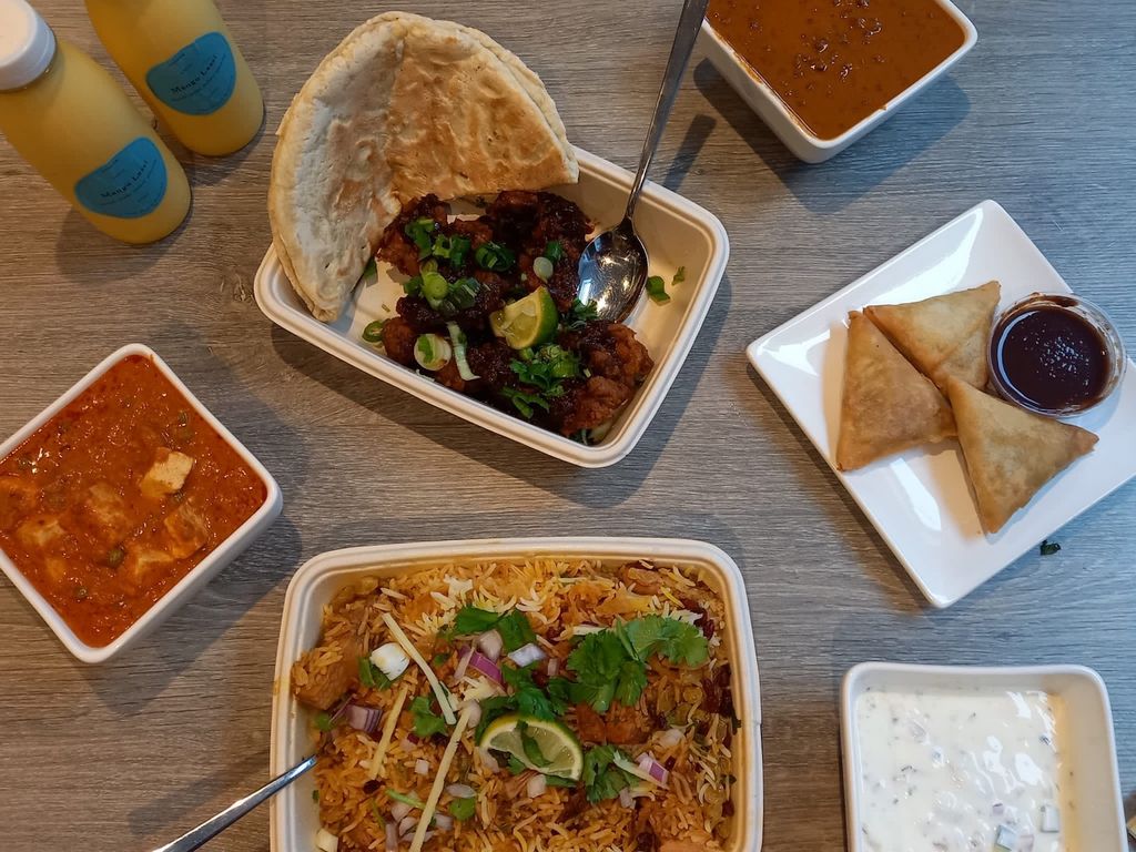 Overhad shot of an Indian takeaway with byriani, black dahl, paneer and samosas