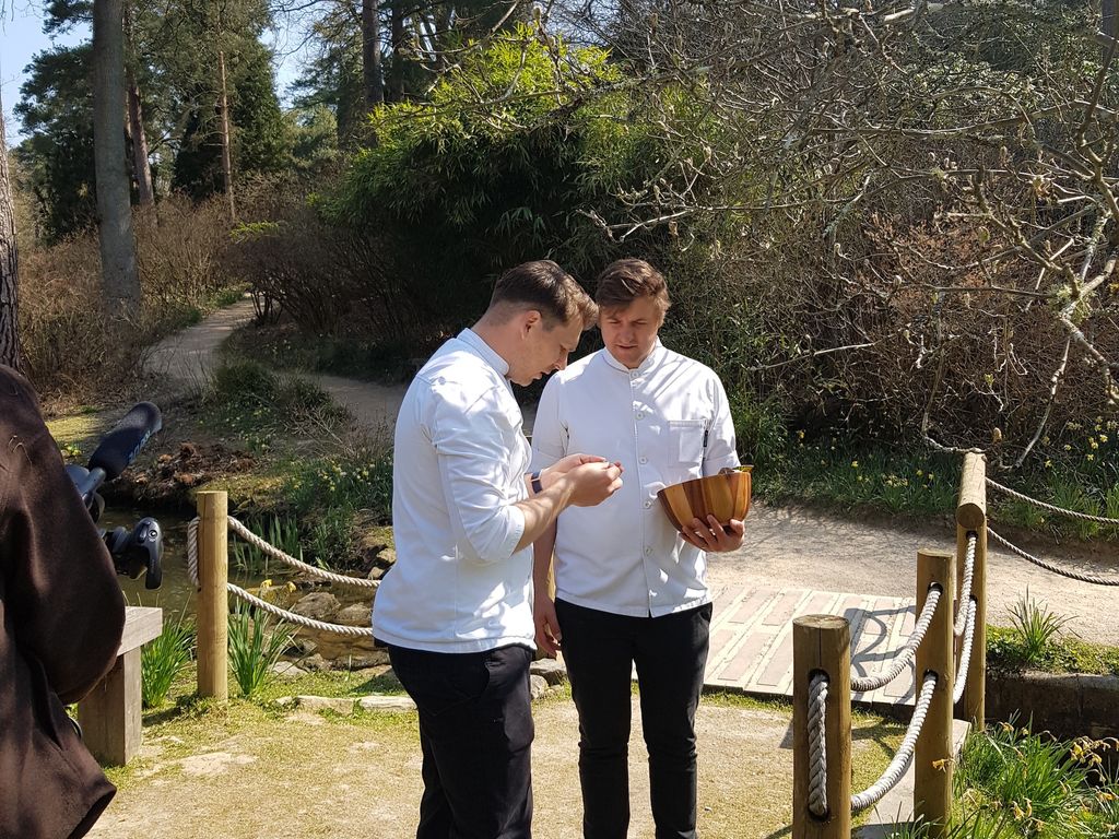 Chefs stood on a bridge holding foraged ingredients