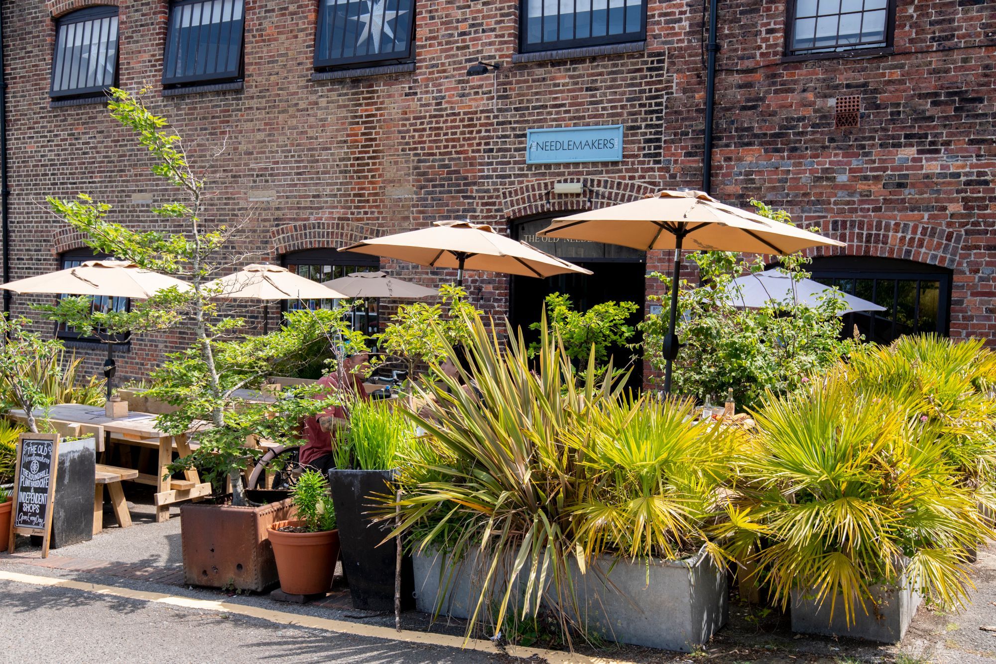 exterior of the Needlemakers, couple of flowerpots in the garden and parasols