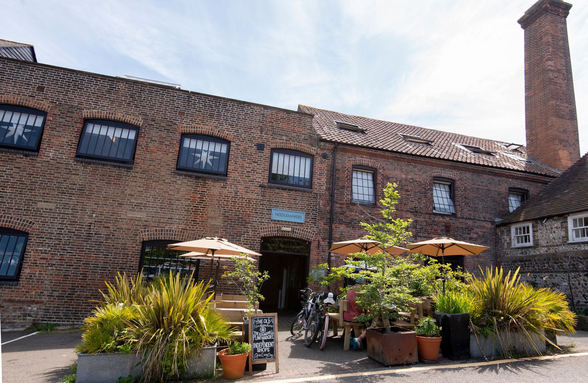 brick building of the needlemakers with exterior seating and and flowerpots