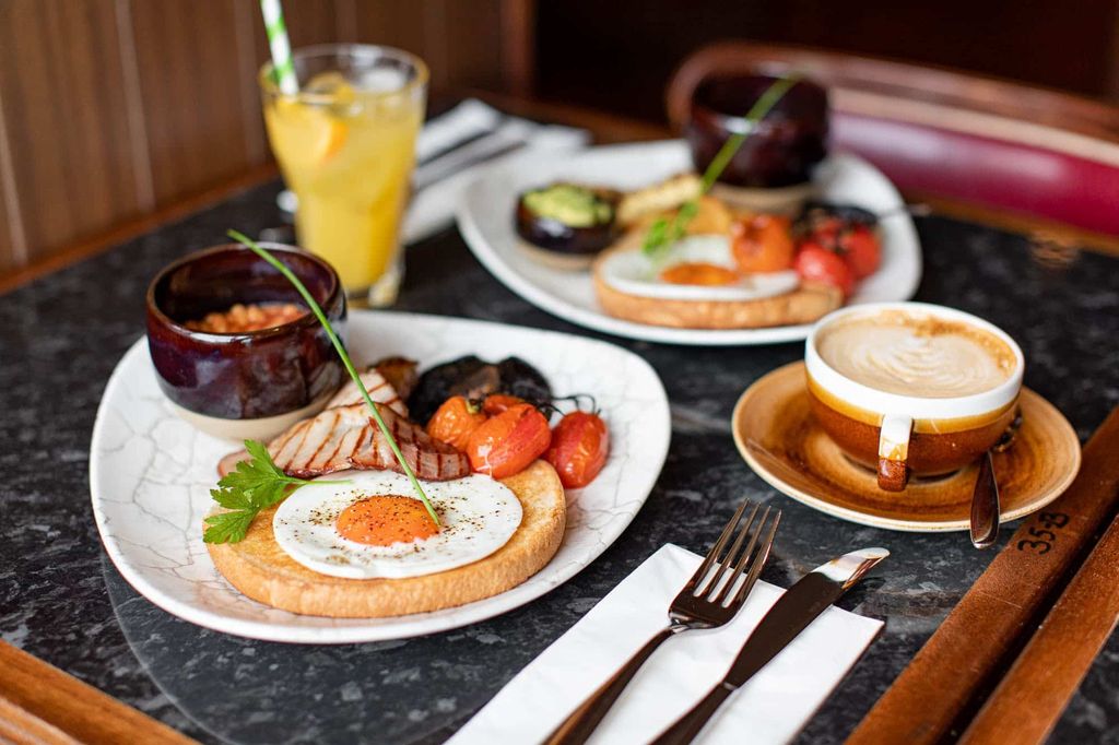 A table laid out with two large Full English breakfasts coffee and juice