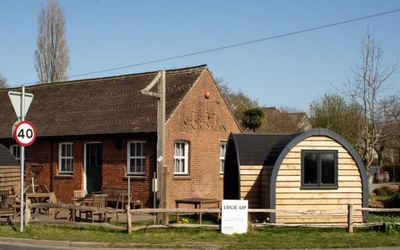 A red brick classic country pub with a wooden dining cabin at the front