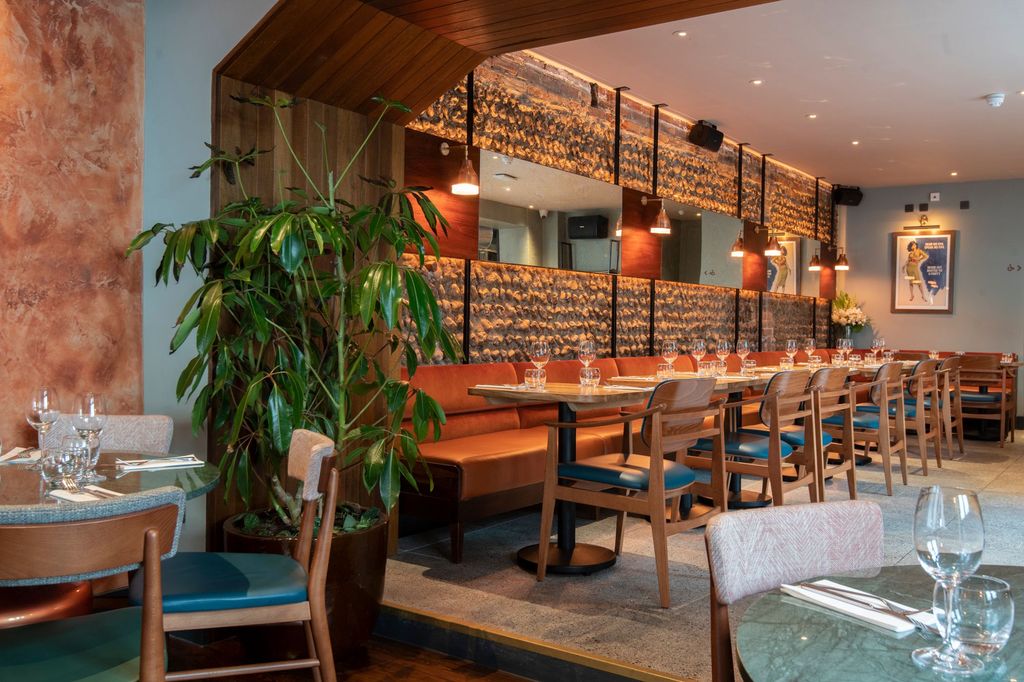 interior of new Brightons restaurant, brown walls decorated with wood and rock, brown tables and loung sofa, brown chairs with dark green seats