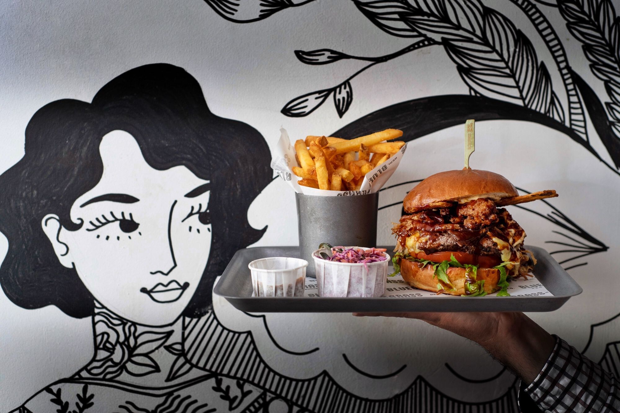 burger and chips on tray with mural in background