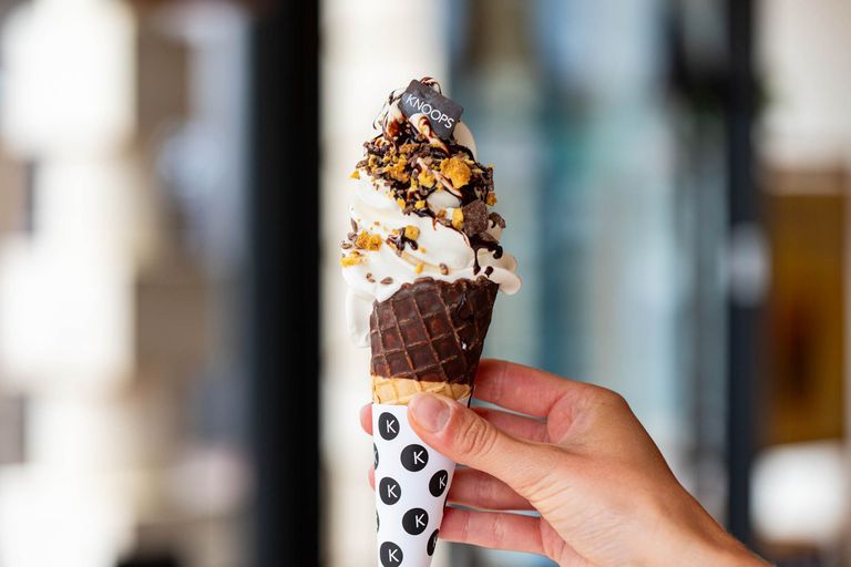The Knoops chocolate covered ice cream. A cornet being held, loaded with chocolate. Knoops is located in Brighton's historic Lanes. Part of our Brighton Ice Cream Guide.