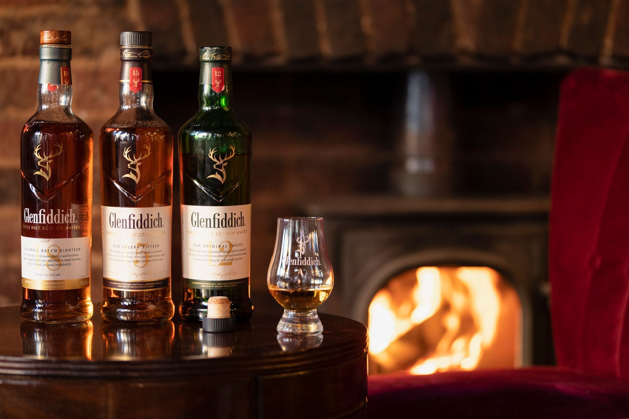three bottles scotch whiskey on the table next to fire place