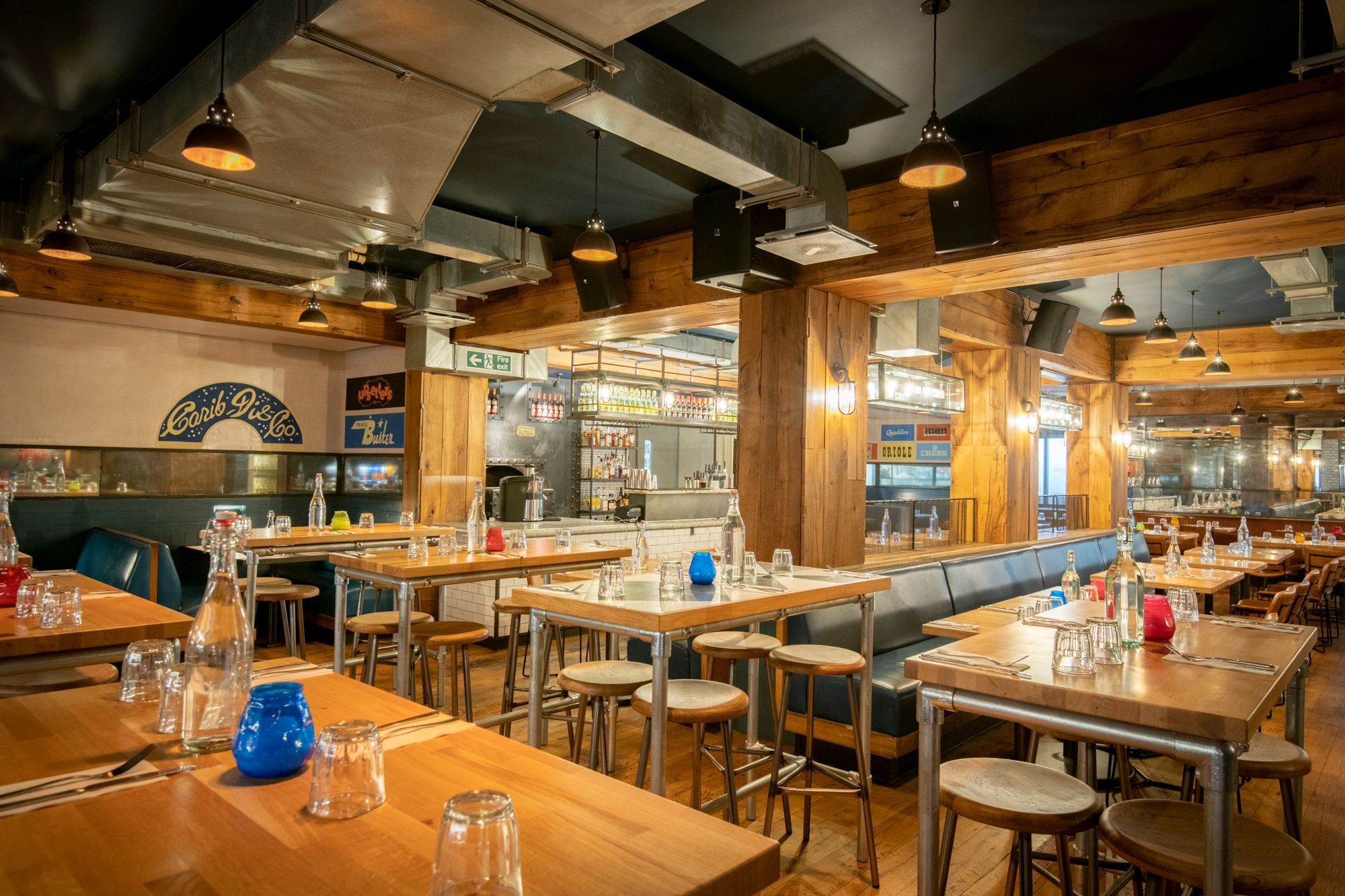 interior of caribbean bar and restaurant the rum kitchen, wooden tables, chairs and bar, red and blue candle glasses