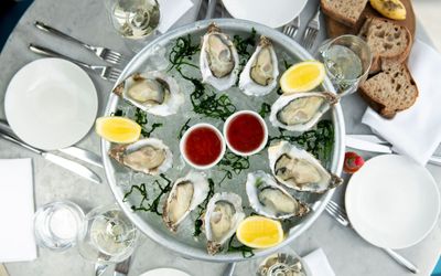 plate with oysters and lemons served with bread and white wine