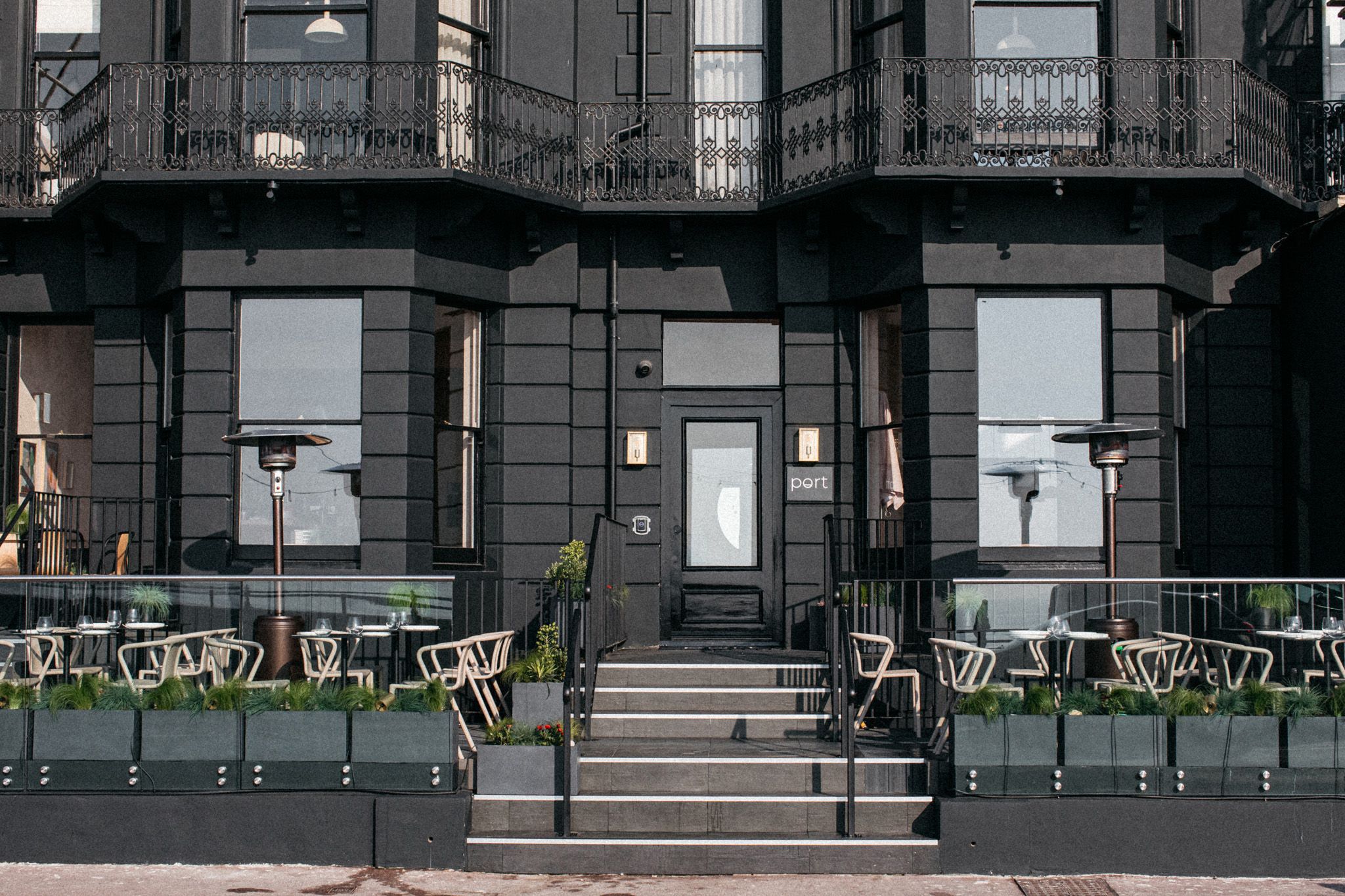 exterior of the Port Hotel in Eastbourne, black looking walls, seating area with white chairs