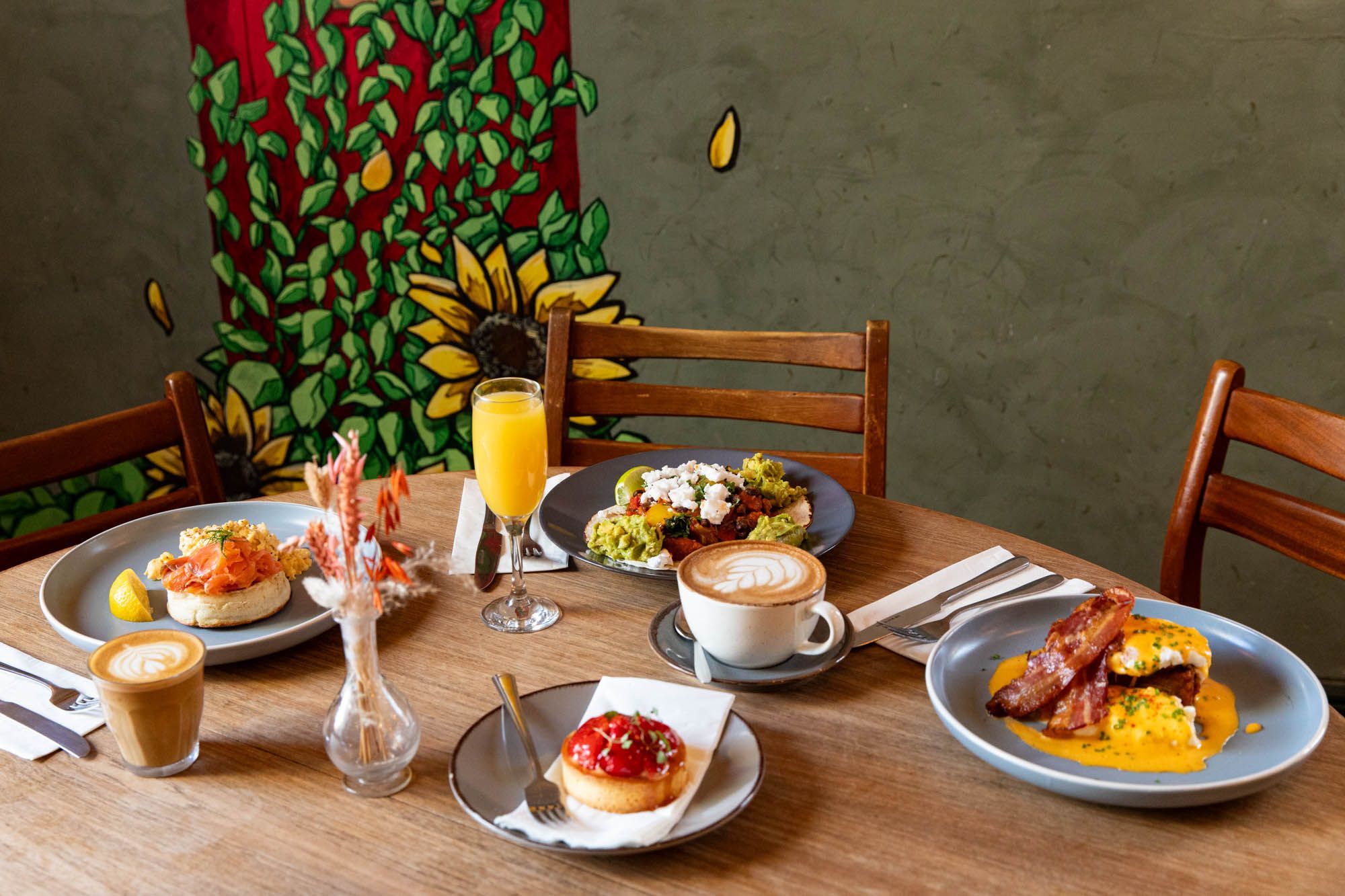 table laid out with the brunch dishes at Post House Brighton including: eggs and bacon, avocado toast, sweet dish, coffee.