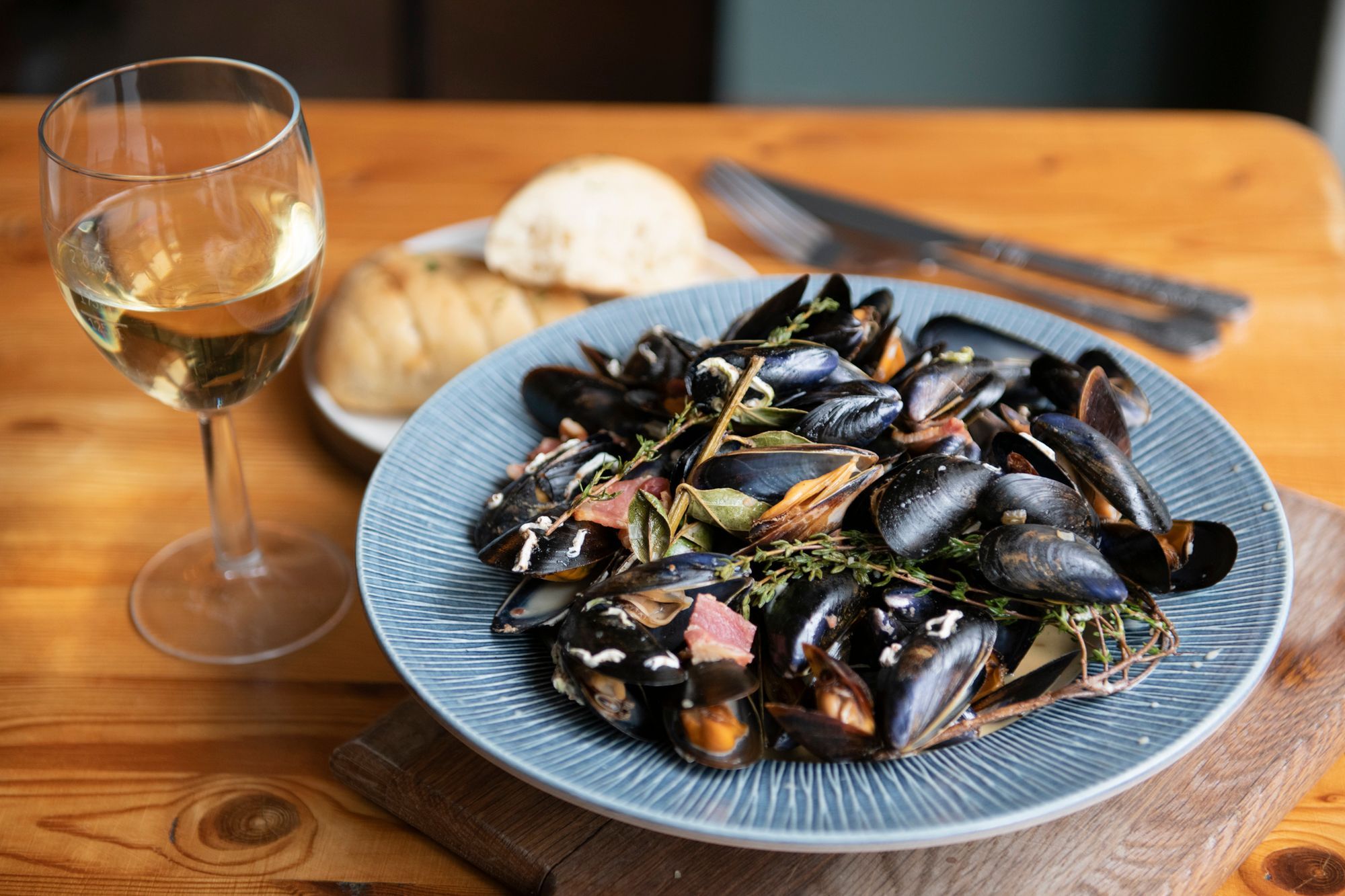 mussels on the blue plate with white wine on the side