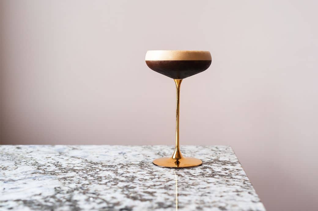 espresso martini in the golden cocktail glass left on the granite looking table - Port Hotel Eastbourne