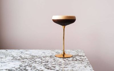espresso martini in the golden cocktail glass left on the granite looking table
