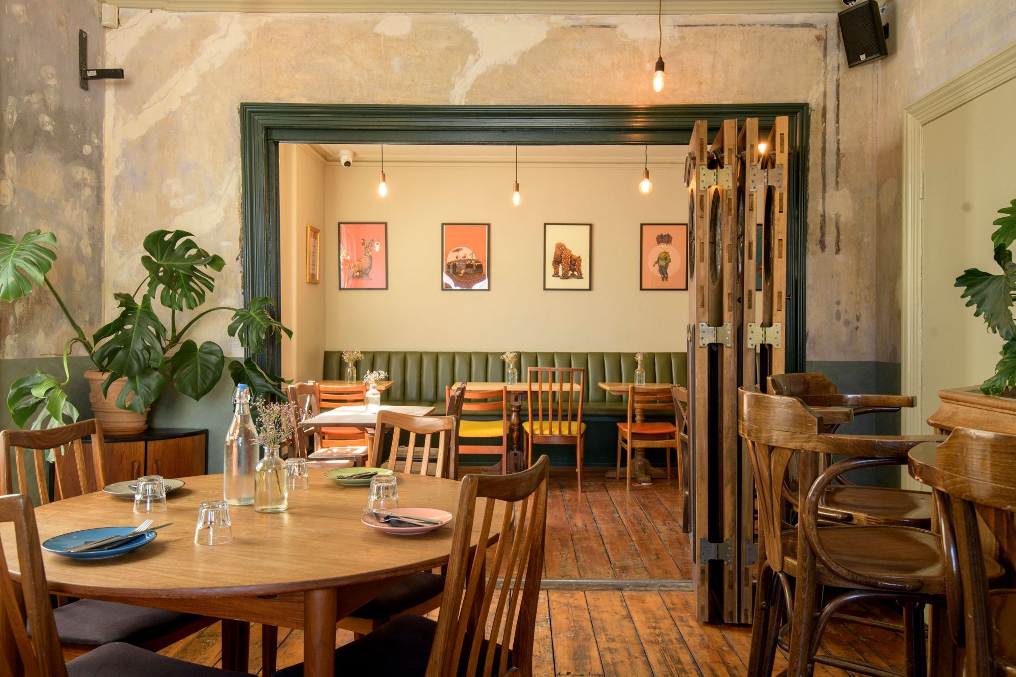 interior of the Post Hose, brown wooden tables and chairs, beige wall with different small paintings hanging on the wall