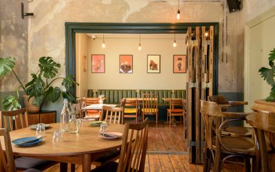 interior of the Post Hose, brown wooden tables and chairs, beige wall with different small paintings hanging on the wall. Featured in our places to eat in Brighton