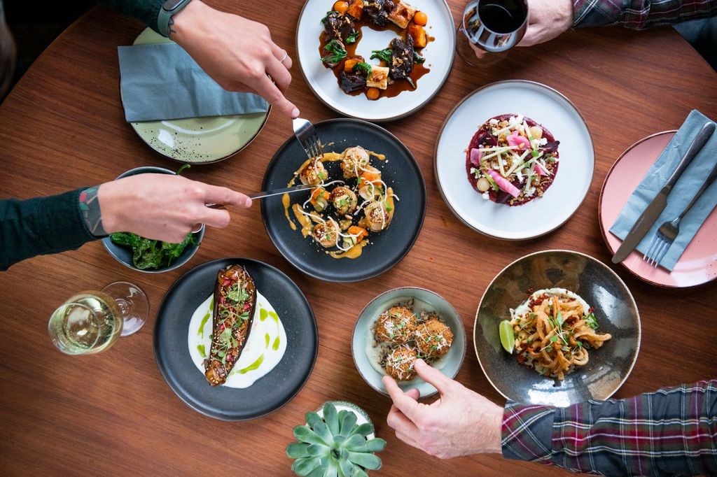 Overhead shot of people dining at the table, six plate with various food served