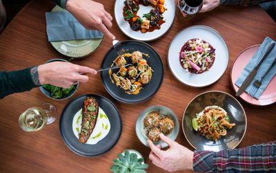 Overhead shot of people dining at the table, six plate with various food served