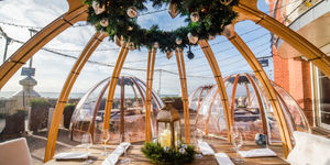 Brighton igloo at Shelter Hall on Brighton seafront. In foreground a wooden table laid for dinner with cutlery and napkins. A perfect option for Valentines Day Brighton